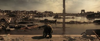 Movie still from “Resident Evil: The Final Chapter” (2016), directed by Paul W.S. Anderson – A man kneeling down on the side of the road near a body of water; Extreme Wide shot, Low angle