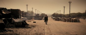 Movie still from “Resident Evil: The Final Chapter” (2016), directed by Paul W.S. Anderson – A person walking down a street holding a gun; Extreme Wide shot, Over the shoulder angle