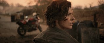 Movie still from “Resident Evil: The Final Chapter” (2016), directed by Paul W.S. Anderson – A person with a motorcycle in the background; Close Up shot, Over the shoulder angle