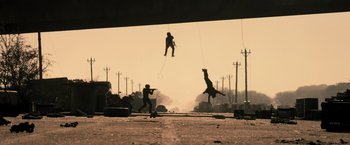 Movie still from “Resident Evil: The Final Chapter” (2016), directed by Paul W.S. Anderson – A giraffe is jumping over a man in the air while another man is standing on the ground; Wide shot, Low angle