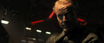 Movie still from “Resident Evil: The Final Chapter” (2016), directed by Paul W.S. Anderson – An older man with a beard and a jacket on; Close Up shot, Over the shoulder angle