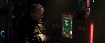 Movie still from “Resident Evil: The Final Chapter” (2016), directed by Paul W.S. Anderson – A man looking at an image of a man in the dark; Close Up shot, Over the shoulder angle