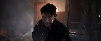 Movie still from “Resident Evil: The Final Chapter” (2016), directed by Paul W.S. Anderson – A man in a black jacket is holding a gun; Close Up shot, Over the shoulder angle