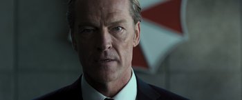 Movie still from “Resident Evil: The Final Chapter” (2016), directed by Paul W.S. Anderson – A man in a suit and tie; Close Up shot, Over the shoulder angle