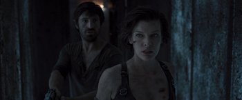 Movie still from “Resident Evil: The Final Chapter” (2016), directed by Paul W.S. Anderson – A man and a woman standing next to each other in a dark room; Close Up shot, Over the shoulder angle