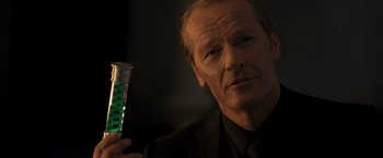 Movie still from “Resident Evil: The Final Chapter” (2016), directed by Paul W.S. Anderson – A man in a black suit holding a green liquid in his hand; Close Up shot, Low angle