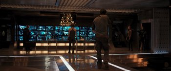 Movie still from “Resident Evil: The Final Chapter” (2016), directed by Paul W.S. Anderson – Two people standing in front of a large screen television display; Wide shot, Over the shoulder angle