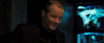 Movie still from “Resident Evil: The Final Chapter” (2016), directed by Paul W.S. Anderson – A person wearing a suit and smiling; Close Up shot, Low angle