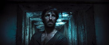 Movie still from “Resident Evil: The Final Chapter” (2016), directed by Paul W.S. Anderson – A man standing in a dark room looking at the camera; Close Up shot, Low angle