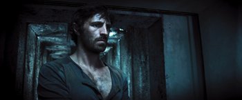 Movie still from “Resident Evil: The Final Chapter” (2016), directed by Paul W.S. Anderson – A man with a beard is standing in a dark room; Close Up shot, Low angle