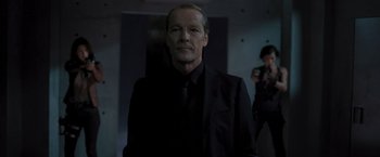 Movie still from “Resident Evil: The Final Chapter” (2016), directed by Paul W.S. Anderson – A man wearing a black suit and tie; Medium shot, Low angle