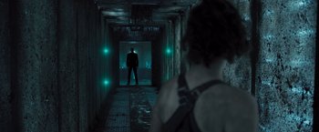 Movie still from “Resident Evil: The Final Chapter” (2016), directed by Paul W.S. Anderson – A woman standing in a dark hallway with green lights; Wide shot, Low angle