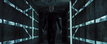 Movie still from “Resident Evil: The Final Chapter” (2016), directed by Paul W.S. Anderson – A man in a black suit walking in a dark room; Medium shot, Low angle
