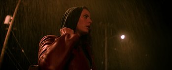 Movie still from “Resident Evil: Welcome to Raccoon City” (2021), directed by Johannes Roberts – A woman in a hooded jacket standing in the rain; Close Up shot, Low angle