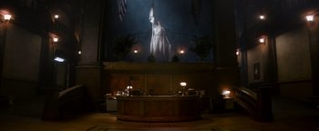 Movie still from “Resident Evil: Welcome to Raccoon City” (2021), directed by Johannes Roberts – A large screen in a large room with a statue on the wall; Extreme Wide shot, Low angle