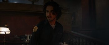 Movie still from “Resident Evil: Welcome to Raccoon City” (2021), directed by Johannes Roberts – A man with long black hair wearing a uniform; Close Up shot, Over the shoulder angle