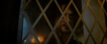 Movie still from “Resident Evil: Welcome to Raccoon City” (2021), directed by Johannes Roberts – A person looking through a lattice window; Close Up shot, Low angle