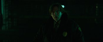 Movie still from “Resident Evil: Welcome to Raccoon City” (2021), directed by Johannes Roberts – A man in a black jacket and a tie in the dark; Close Up shot, Low angle