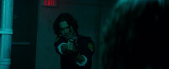 Movie still from “Resident Evil: Welcome to Raccoon City” (2021), directed by Johannes Roberts – A man holding a gun while standing in a dark room; Medium shot, Over the shoulder angle
