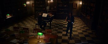 Movie still from “Resident Evil: Welcome to Raccoon City” (2021), directed by Johannes Roberts – Two people are playing piano in a room; Wide shot, High angle