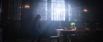 Movie still from “Resident Evil: Welcome to Raccoon City” (2021), directed by Johannes Roberts – A woman standing in front of a table in a room with sunlight coming through the window; Wide shot, Low angle