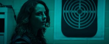 Movie still from “Resident Evil: Welcome to Raccoon City” (2021), directed by Johannes Roberts – A woman with curly brown hair stares into the distance; Close Up shot, Over the shoulder angle