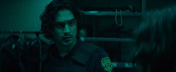 Movie still from “Resident Evil: Welcome to Raccoon City” (2021), directed by Johannes Roberts – A man in a police uniform is looking at the camera; Close Up shot, Over the shoulder angle