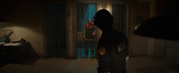 Movie still from “Resident Evil: Welcome to Raccoon City” (2021), directed by Johannes Roberts – A man standing in front of a jail cell; Wide shot, Over the shoulder angle