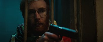 Movie still from “Resident Evil: Welcome to Raccoon City” (2021), directed by Johannes Roberts – A man with a beard holding a gun in his hand; Close Up shot, Low angle