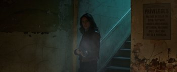 Movie still from “Resident Evil: Welcome to Raccoon City” (2021), directed by Johannes Roberts – A man standing in a dark room holding a gun; Medium shot, Low angle