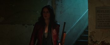 Movie still from “Resident Evil: Welcome to Raccoon City” (2021), directed by Johannes Roberts – A woman holding a rifle in a dark room; Medium shot, Low angle