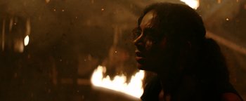 Movie still from “Resident Evil: Welcome to Raccoon City” (2021), directed by Johannes Roberts – A woman with glasses is in front of a fire; Close Up shot, Low angle