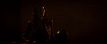 Movie still from “Resident Evil: Welcome to Raccoon City” (2021), directed by Johannes Roberts – A woman in a leather jacket standing in a dark room; Medium shot, Over the shoulder angle