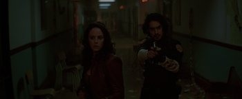 Movie still from “Resident Evil: Welcome to Raccoon City” (2021), directed by Johannes Roberts – A man and a woman are walking in a dark room; Medium shot, Over the shoulder angle