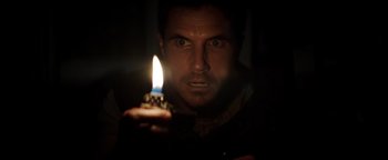Movie still from “Resident Evil: Welcome to Raccoon City” (2021), directed by Johannes Roberts – A man holding a lit candle in a dark room; Close Up shot, High angle