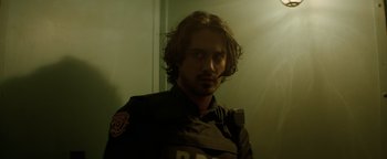 Movie still from “Resident Evil: Welcome to Raccoon City” (2021), directed by Johannes Roberts – A man with long brown hair is standing in front of a mirror; Close Up shot, Low angle
