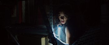 Movie still from “Resident Evil: Welcome to Raccoon City” (2021), directed by Johannes Roberts – A woman is holding a flashlight in a dark room; Medium shot, Low angle