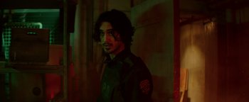 Movie still from “Resident Evil: Welcome to Raccoon City” (2021), directed by Johannes Roberts – A man with long black hair is standing in the dark; Close Up shot, Over the shoulder angle