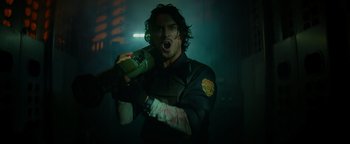 Movie still from “Resident Evil: Welcome to Raccoon City” (2021), directed by Johannes Roberts – A man holding a bottle in a dark room; Medium shot, Low angle