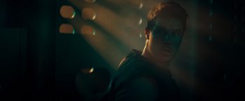 Movie still from “Resident Evil: Welcome to Raccoon City” (2021), directed by Johannes Roberts – A man in a black shirt and some lights in the background; Close Up shot, Low angle