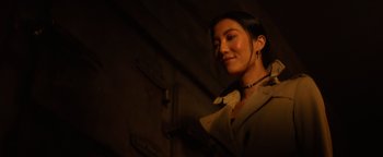 Movie still from “Resident Evil: Welcome to Raccoon City” (2021), directed by Johannes Roberts – A woman with a necklace standing in the dark; Close Up shot, Over the shoulder angle