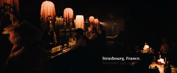 Movie still from “Resistance” (2020), directed by Jonathan Jakubowicz – People are sitting at a bar at night time; Wide shot, High angle