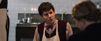 Movie still from “Resistance” (2020), directed by Jonathan Jakubowicz – A man with curly brown hair wearing an apron; Close Up shot, Over the shoulder angle