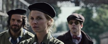 Movie still from “Resistance” (2020), directed by Jonathan Jakubowicz – A woman wearing a black hat and a man wearing a black hat; Close Up shot, Low angle