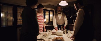 Movie still from “Resistance” (2020), directed by Jonathan Jakubowicz – A group of people standing around a dinner table; Medium shot, Over the shoulder angle