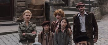 Movie still from “Resistance” (2020), directed by Jonathan Jakubowicz – A group of people standing next to each other on a street; Medium shot, Low angle