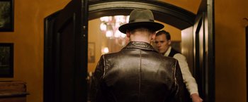 Movie still from “Resistance” (2020), directed by Jonathan Jakubowicz – A man in a hat and a leather jacket looking in a mirror; Medium shot, Over the shoulder angle