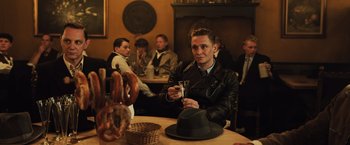 Movie still from “Resistance” (2020), directed by Jonathan Jakubowicz – A man sitting at a table in a restaurant; Medium shot, Over the shoulder angle