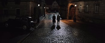 Movie still from “Resistance” (2020), directed by Jonathan Jakubowicz – Two people are walking down a street at night; Extreme Wide shot, High angle