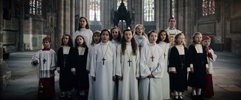 Movie still from “Resistance” (2020), directed by Jonathan Jakubowicz – A group of young girls dressed in white standing next to each other in front of an ornate altar; Medium shot, High angle